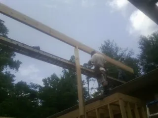 Carpenter setting a ridge beam over a new addition frame — Ice Dam Removal by Roofing Brothers in Burr Hill