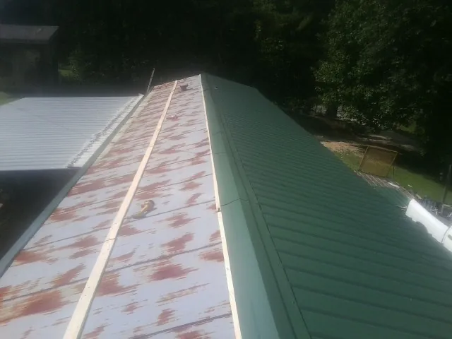 Old rusted panels beside newly installed green metal roofing — Wind Damage Roof Repair by Roofing Brothers in Burr Hill