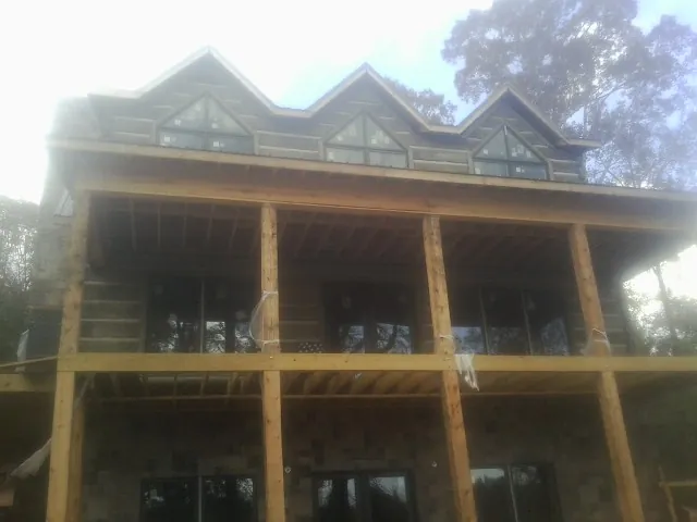 Dormers and porch framing on a large log home under construction — Roof Coating work by our crew in Burr Hill