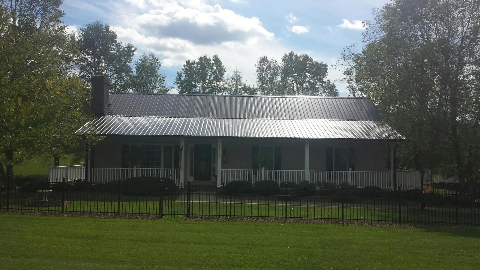 Gray metal roof on a brick ranch with a full width front porch — Gutter Guard Installation work by our crew in Burr Hill