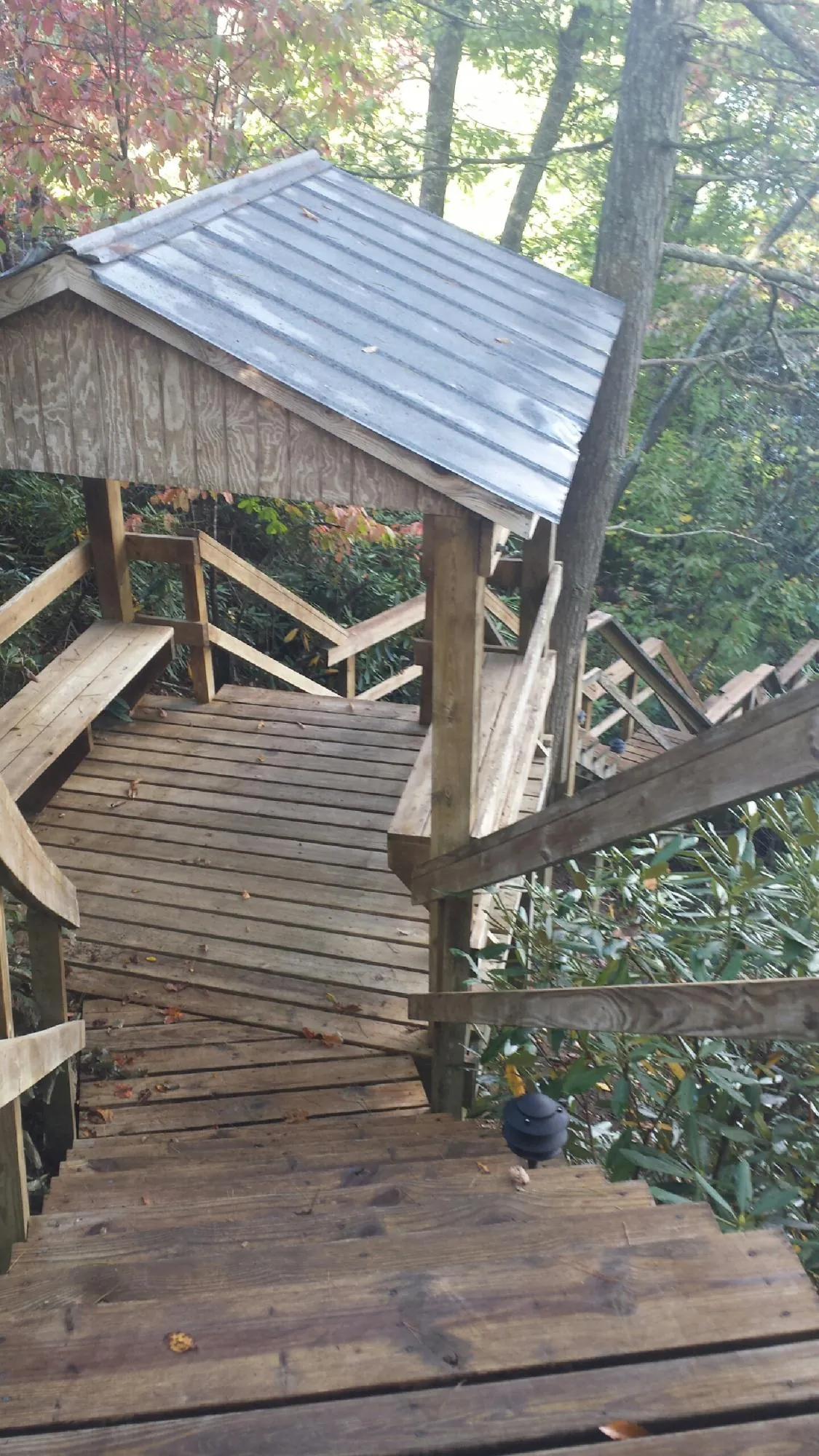 Metal roofed shelter over wooden steps on a wooded walkway — Skylight Repair & Installation work by our crew in Burr Hill