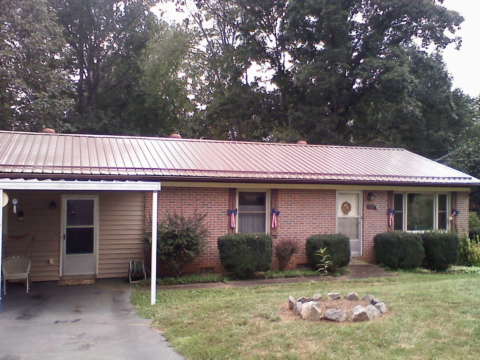 Bronze metal roof and carport on a brick ranch home — Roof Repair work by our crew in Burr Hill