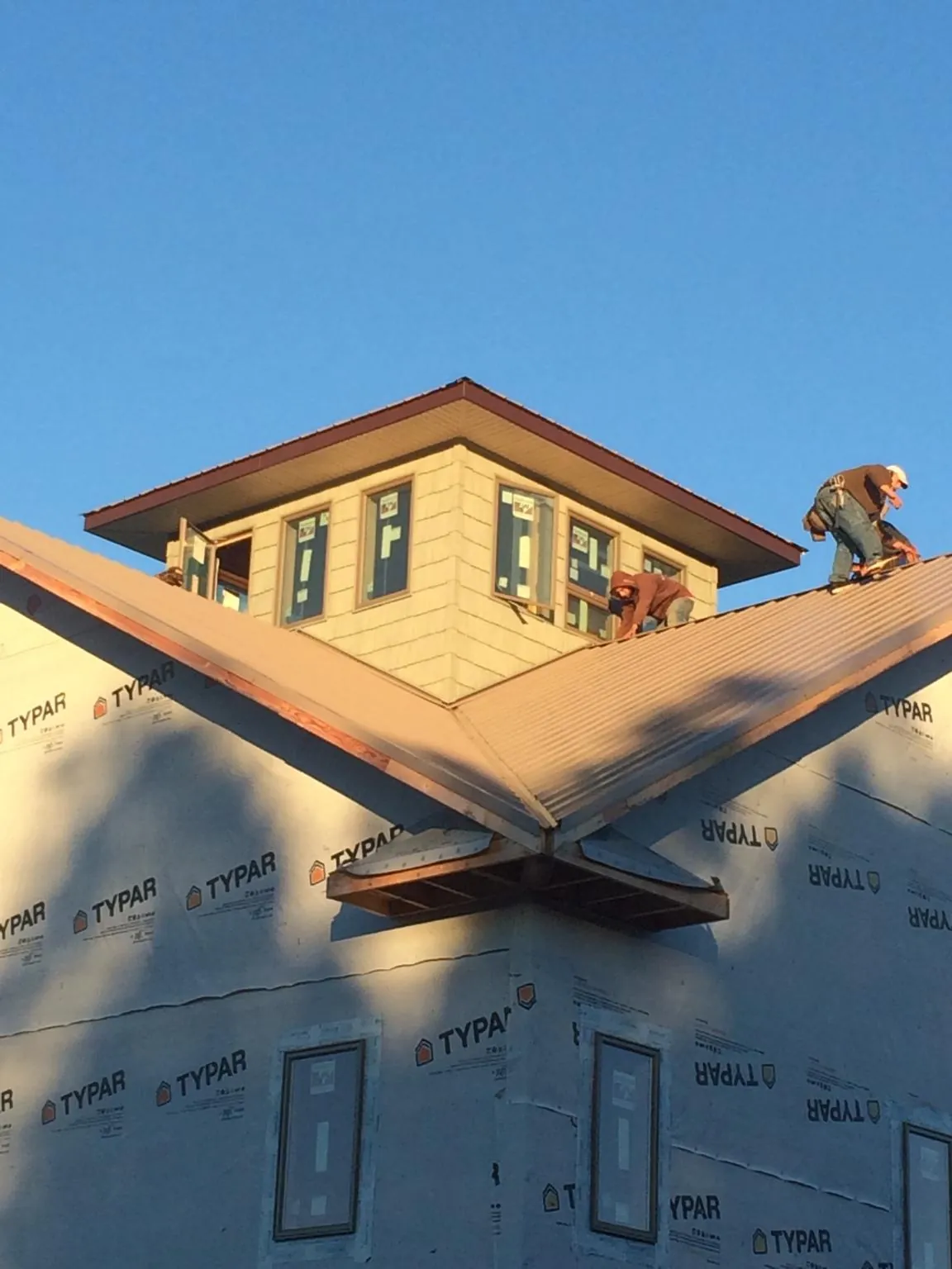 Roofers working around a rooftop cupola on a new metal roof at sunset — Roof Waterproofing in Burr Hill by Roofing Brothers